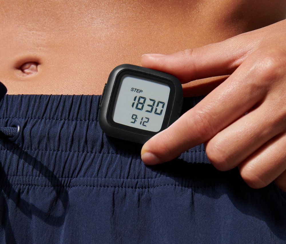 Žena drží v ruce krokoměr.