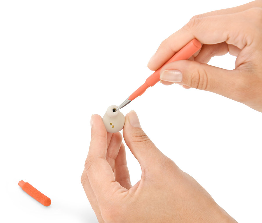 Ruce čistí sluchátko pomocí sady na čištění psacího stolu 4 v 1.