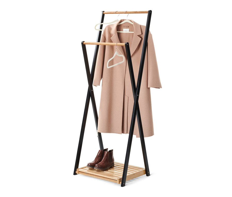 Kabát visí na ramínku na věšáku na šaty a pod ním jsou boty.