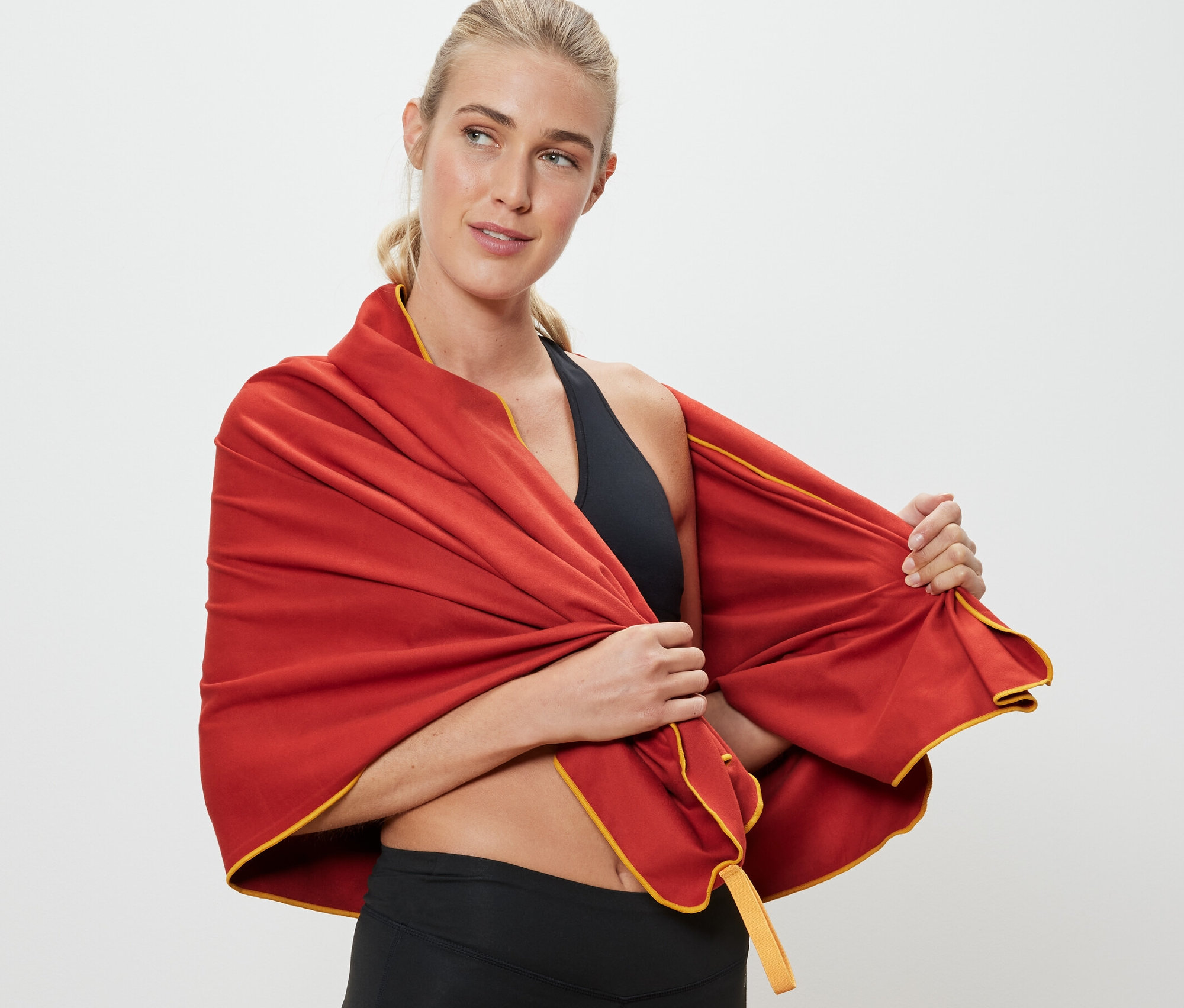 Blondýna si přehazuje přes ramena oranžový outdoorový ručník, cca 70 x 140 cm.