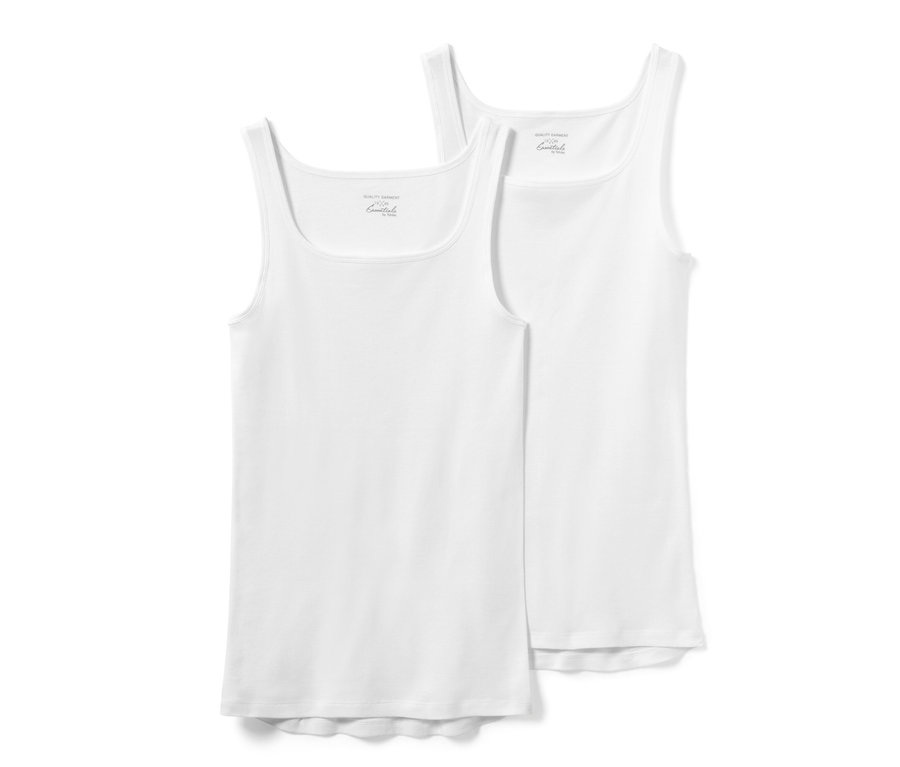 Dvě bílá tílka z jemně žebrované pleteniny.