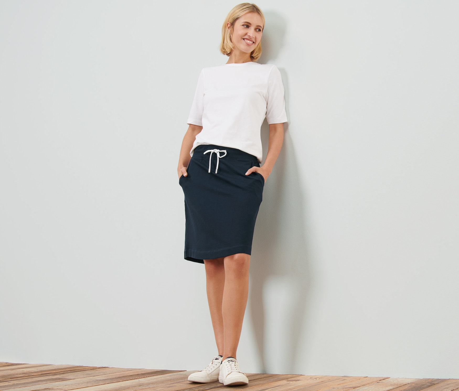 Žena pózuje v teplákové sukni.