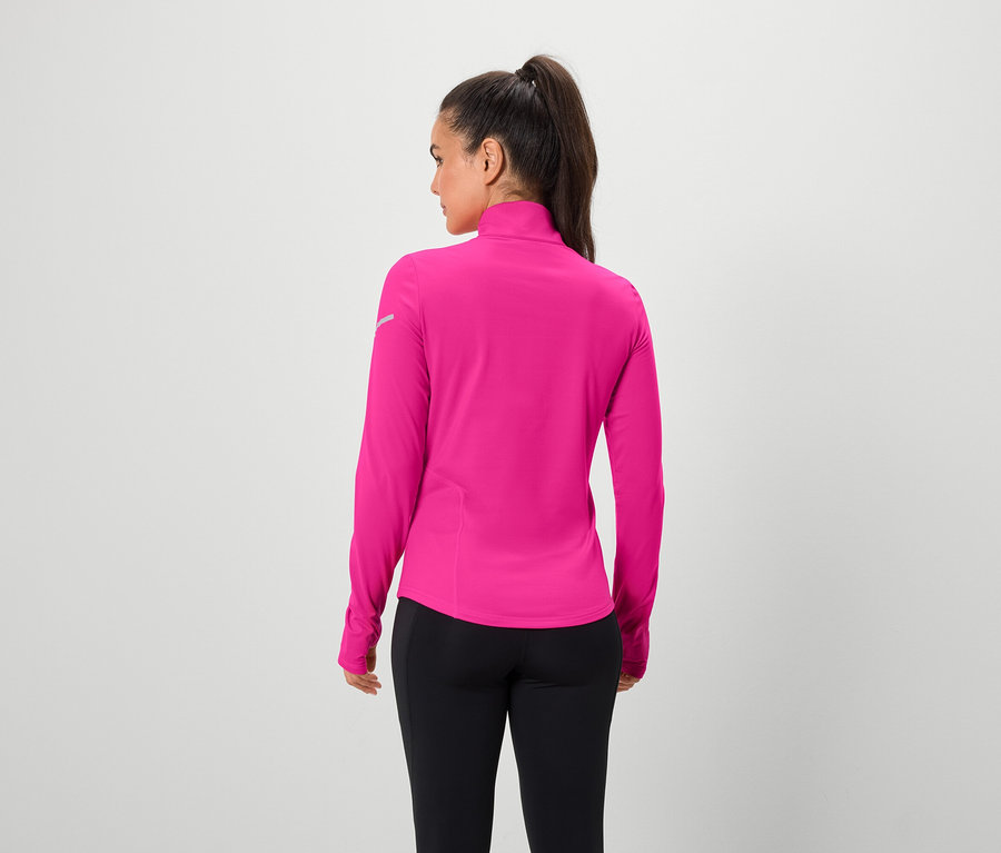 Žena zády k fotoaparátu má na sobě růžový top s dlouhým rukávem a černé legíny.