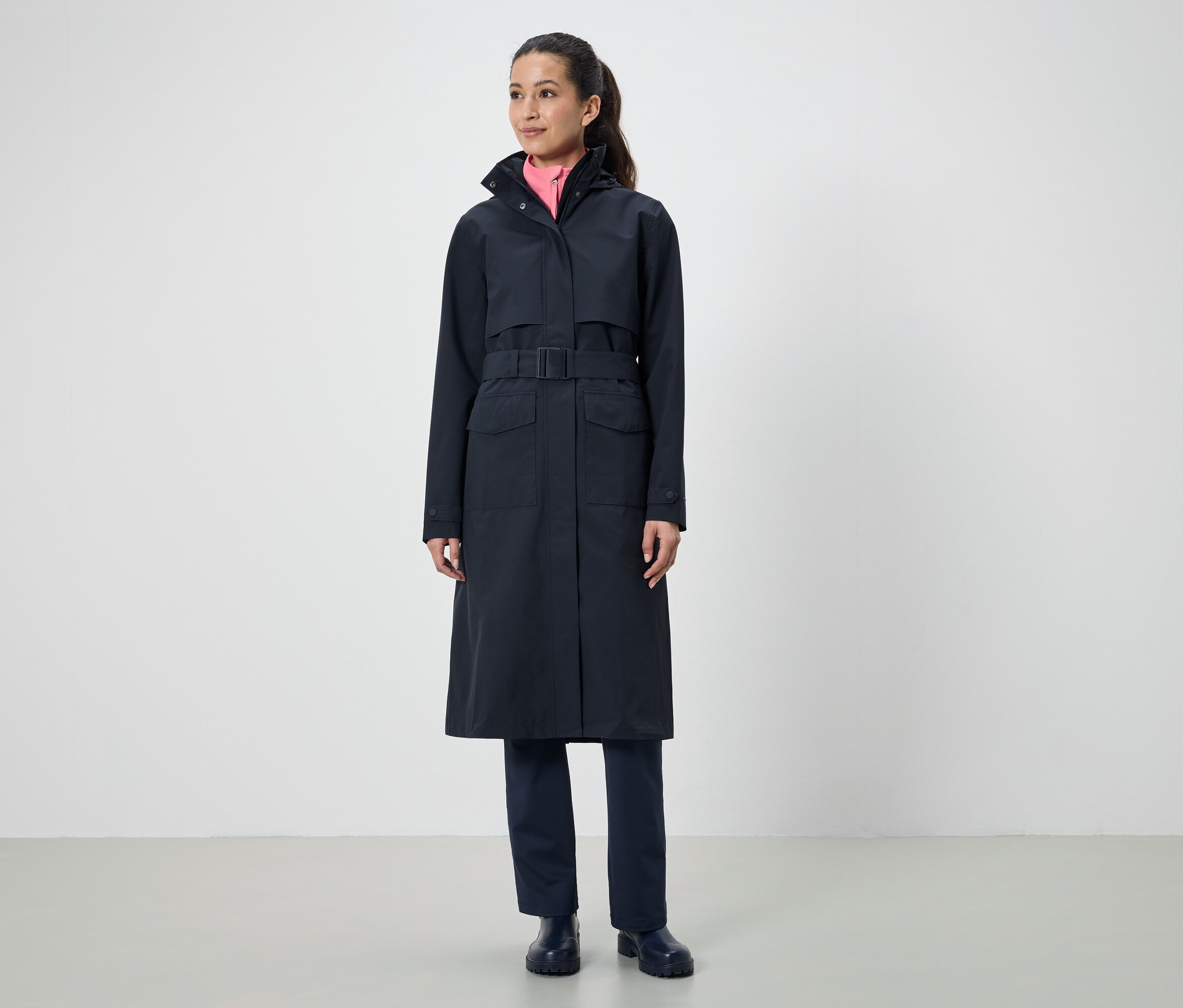 Žena má na sobě dlouhý černý kabát s páskem.