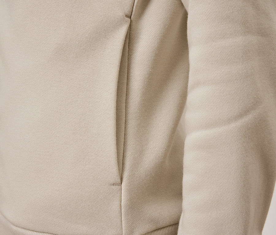 Detail béžové mikiny s kapsou.
