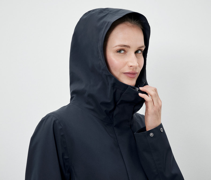 Žena má na sobě tmavě modrou bundu s kapucí.