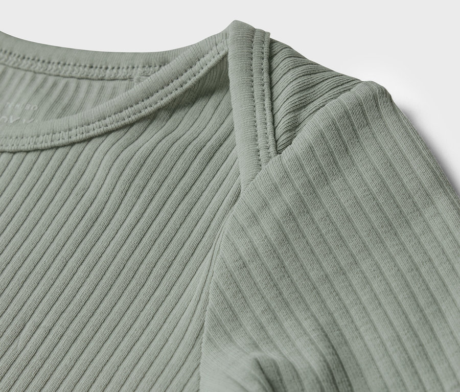 Detail světle zeleného žebrovaného trička s dlouhým rukávem pro miminka.