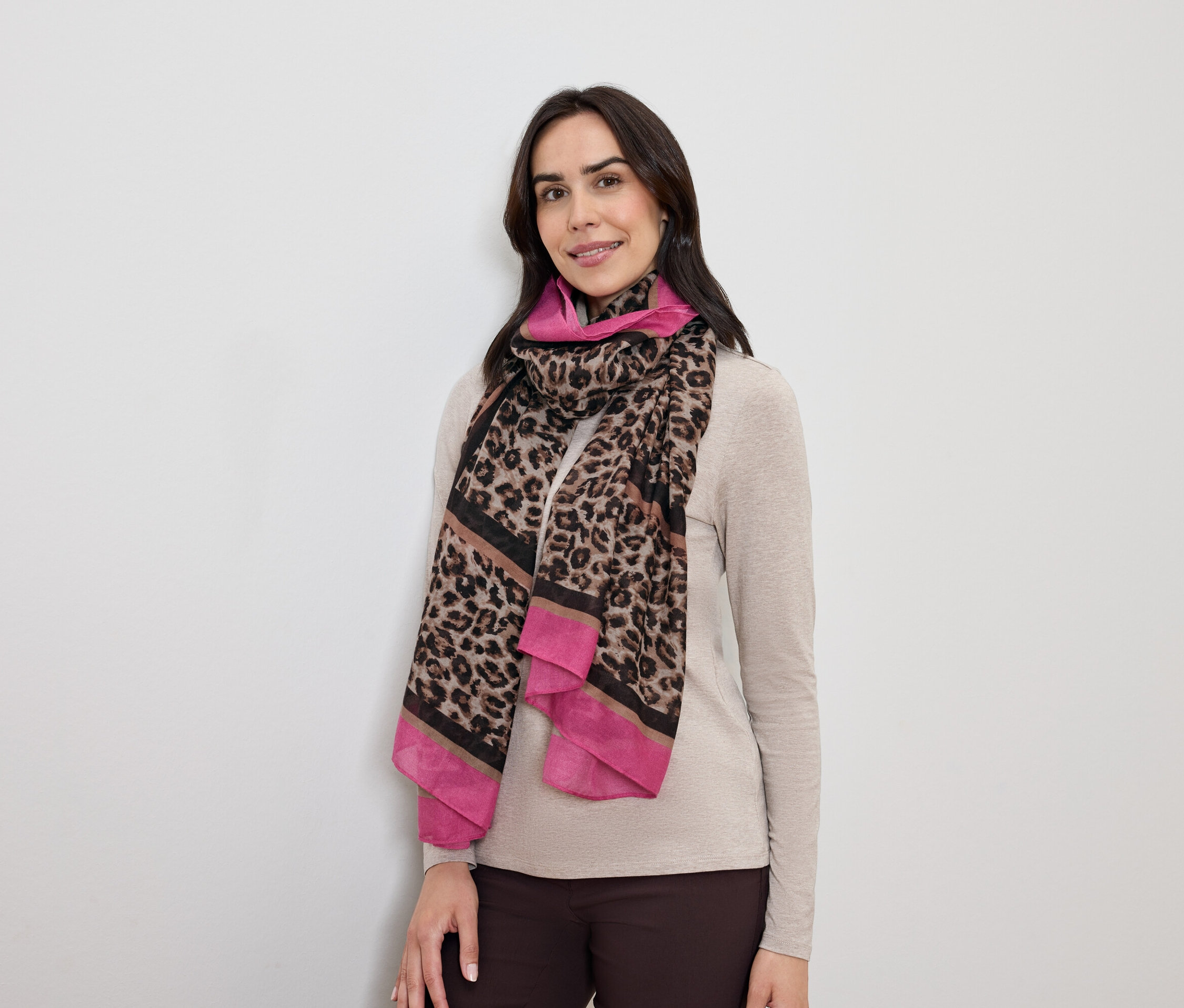 Žena s tmavými vlasy pózuje s leopardím šátkem s růžovými akcenty.