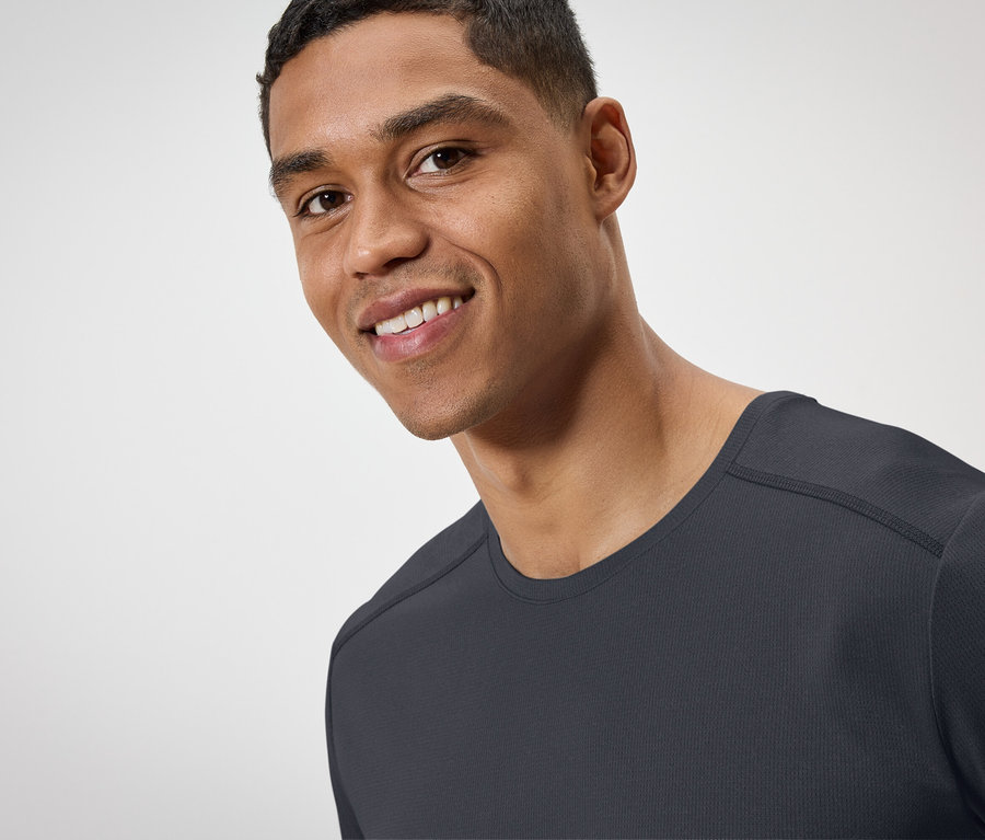 Portrét usmívajícího se muže v černém tričku.