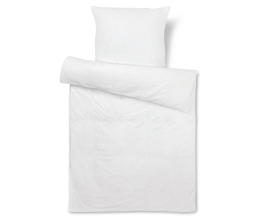 Bílé povlečení na postel s polštářem nahoře.