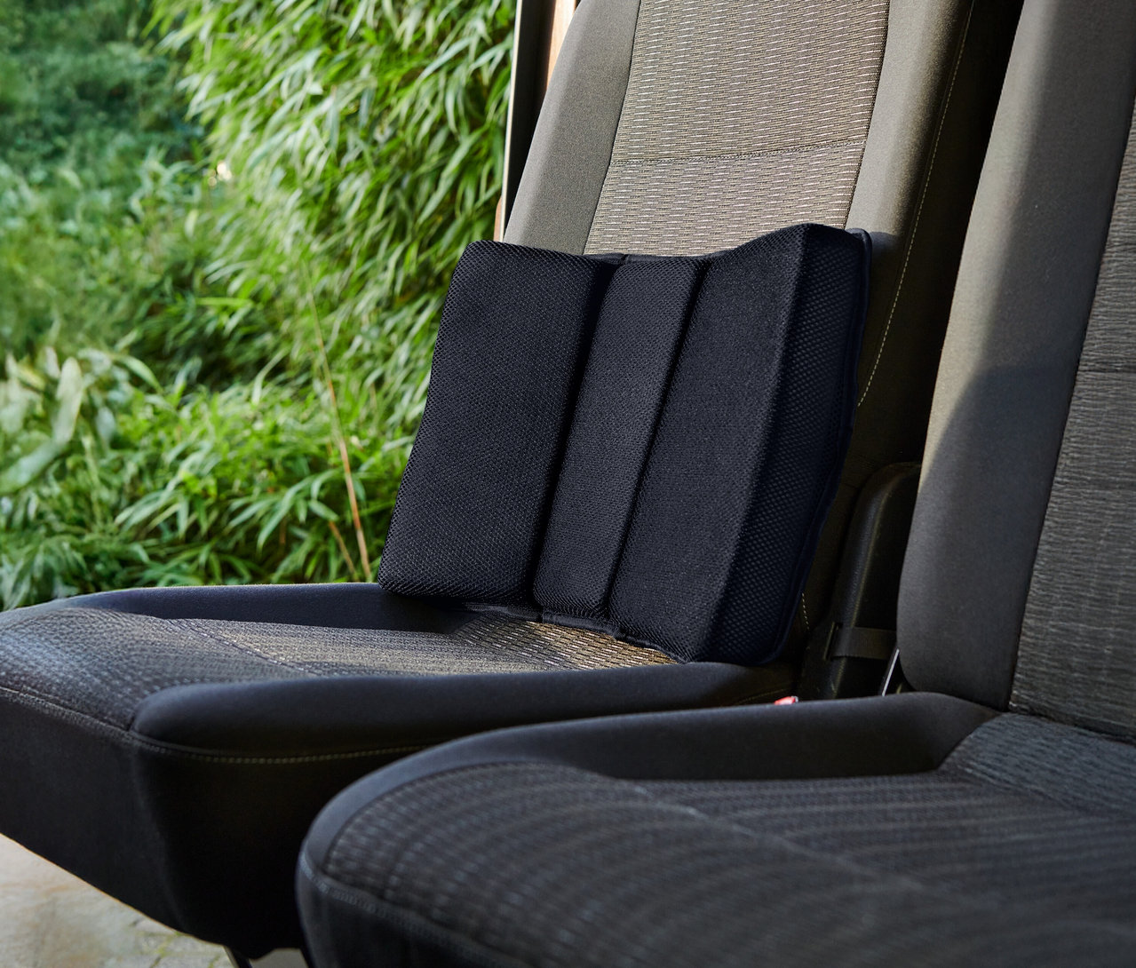Černý bederní polštář umístěný na autosedačce.