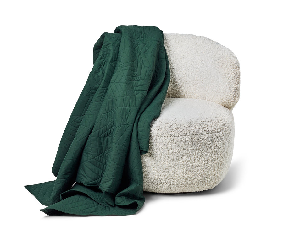 Tmavě zelený prošívaný přehoz na postel (230 x 250 cm) leží na bílém křesle.