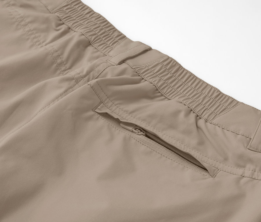 Detail béžových funkčních kalhot 2 v 1 se zipovou kapsou.