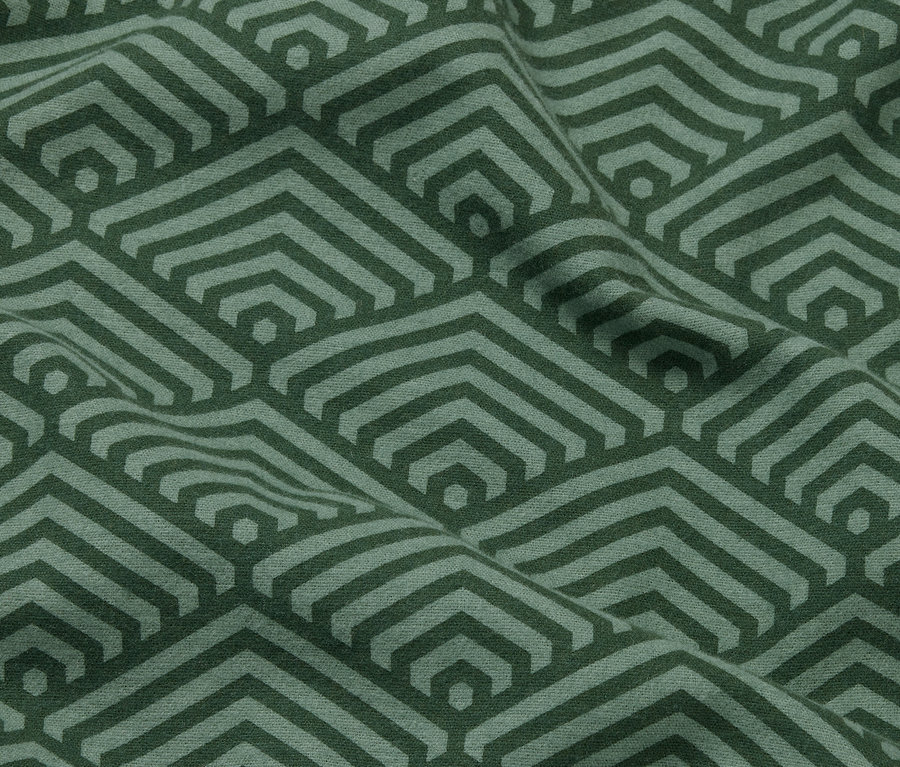 Detailní záběr na dva zelené povlaky na polštáře z biberu s geometrickým vzorem.