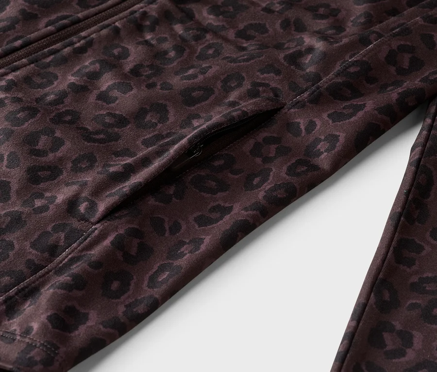 Detail hnědé bundy se zipem a leopardím vzorem, včetně kapsy na zip.