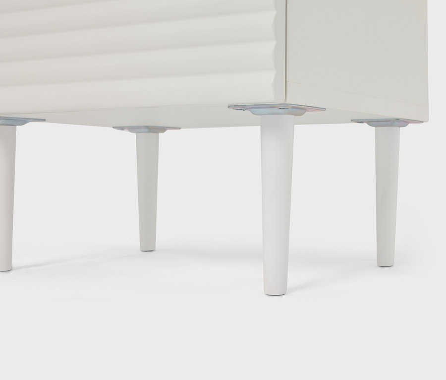 Detailní pohled na bílou skříňku se čtyřmi kuželovými nohami.