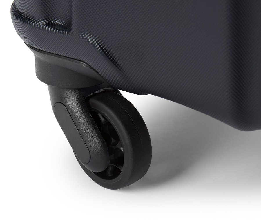 Detailní záběr černého kolečka kufru na bílém pozadí.