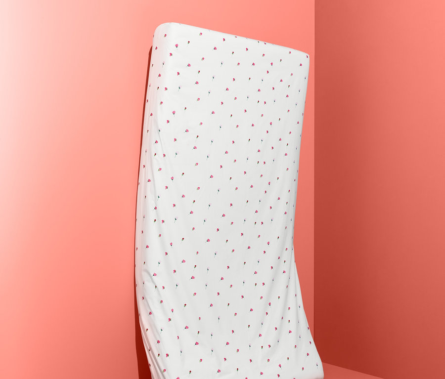 Bílé prostěradlo s červenými puntíky stojí opřené o stěnu.