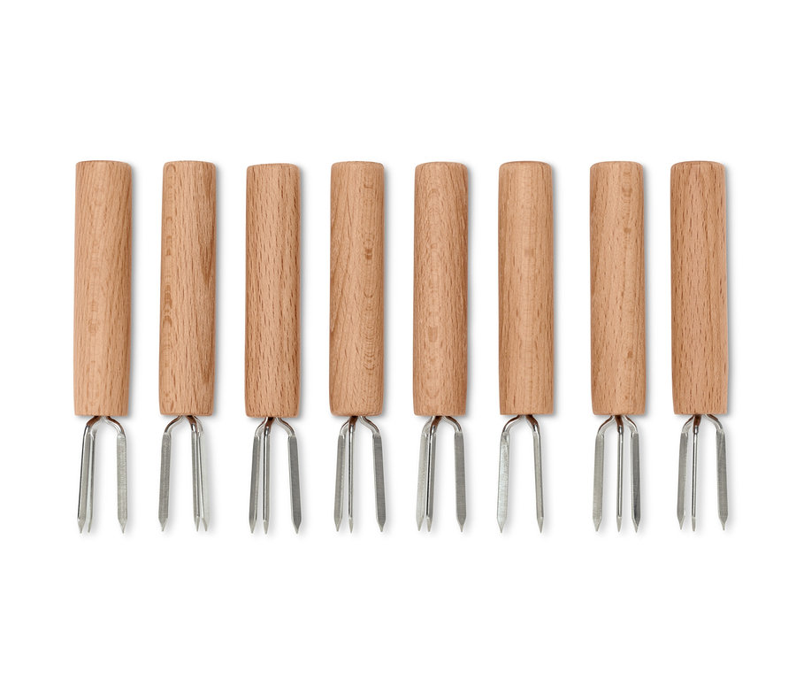 Osm držáků na kukuřici s dřevěnou rukojetí a stříbrnými hroty uspořádaných v řadě.