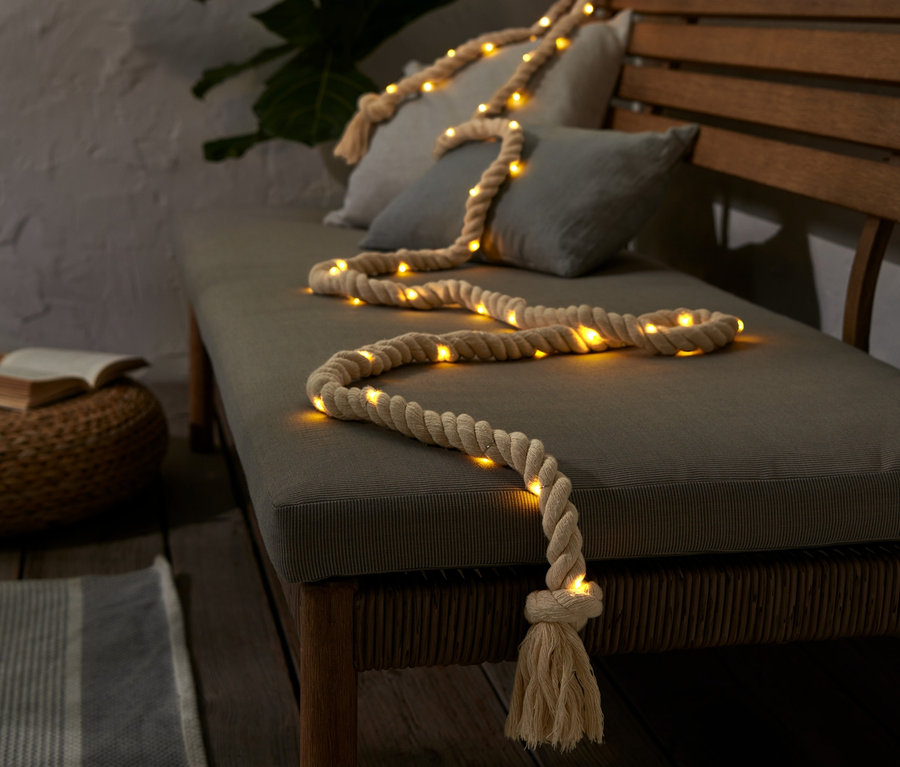 LED světelný řetěz Lano leží na lavici s polštáři.