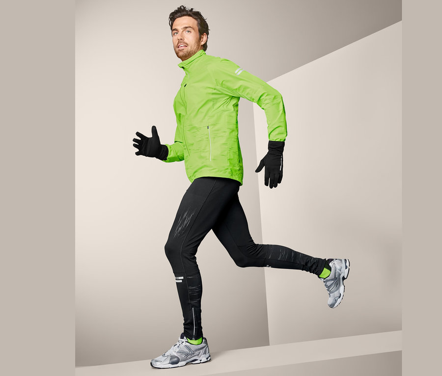 Muž v běžecké pozici má na sobě neonově zelenou bundu a funkční termolegíny.