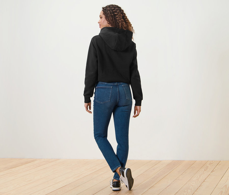Žena zezadu v modrých džínách skinny Fit »Hanna« a černé mikině s kapucí.
