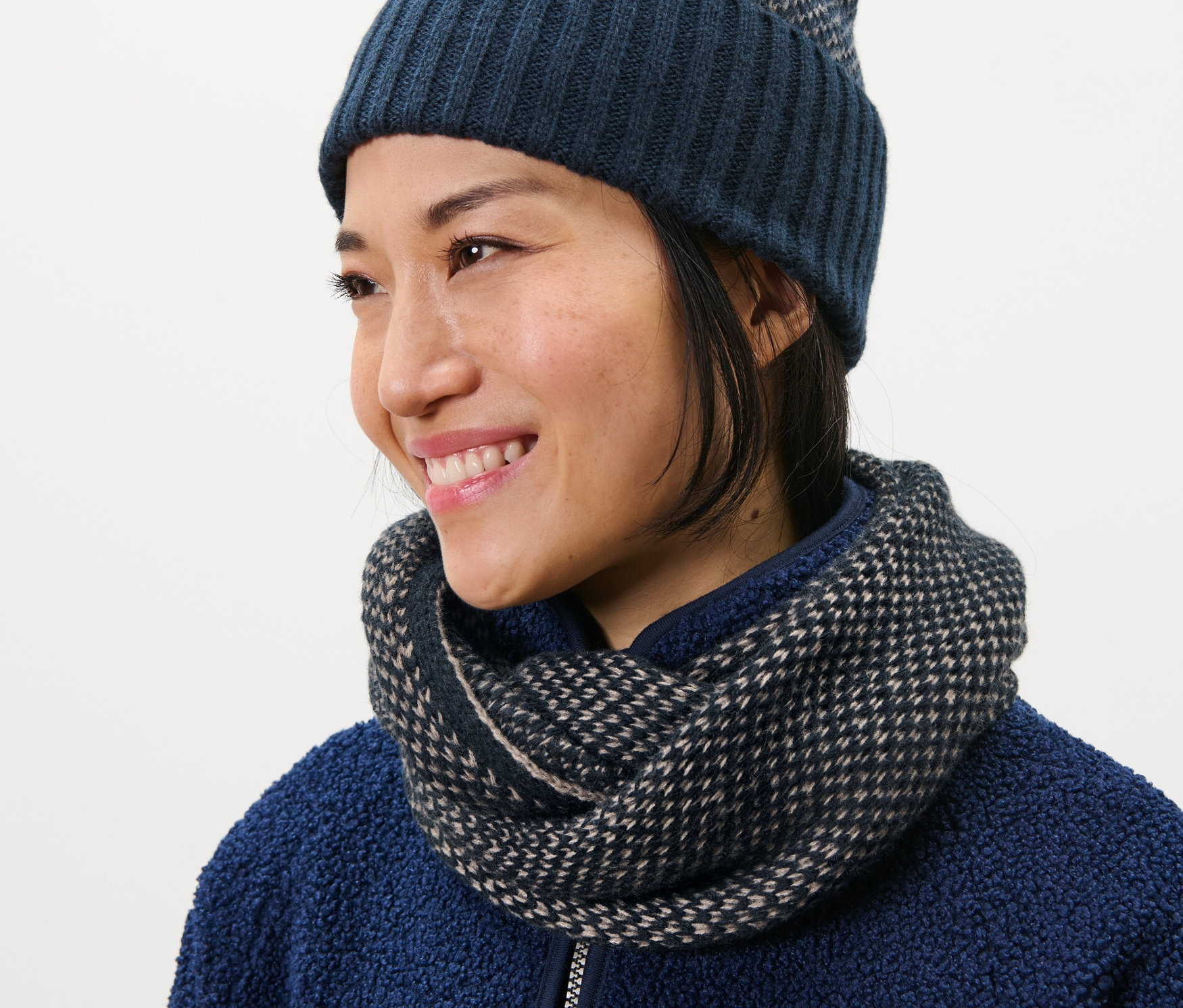 Žena má na sobě pletenou kruhovou šálu a čepici.