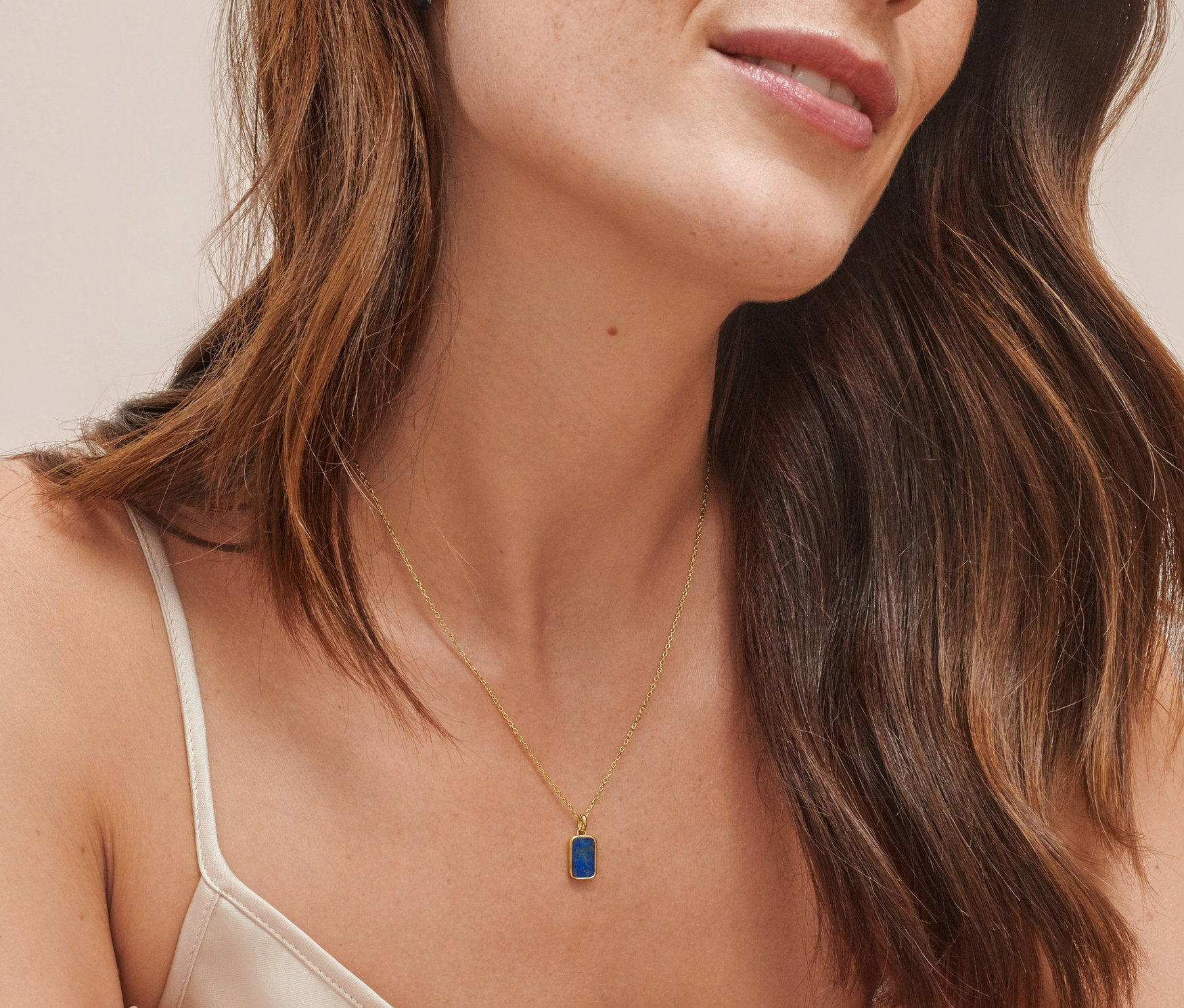 Žena má na sobě kreolky z dvoubarevného stříbra 925/1000 a náhrdelník z pozlaceného stříbra 925/1000 s lapisem lazuli.