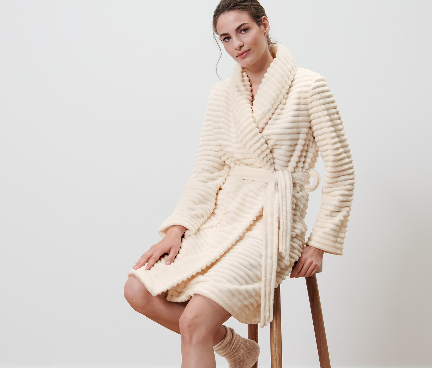 Žena sedí na stoličce a má na sobě župan.