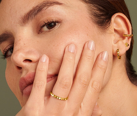 Žena se stříbrným prstenem 925 pyramida na prsteníčku, stříbrnými kreolkami 925 pyramida a stříbrnými náušnicemi 925 ear cuff pyramida.