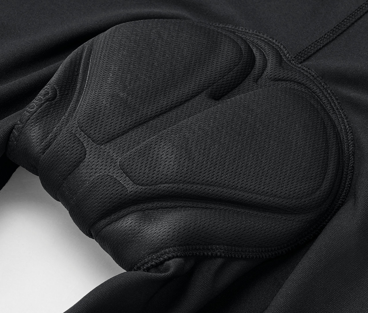 Detailní záběr na černé cyklistické kalhoty s polstrováním.