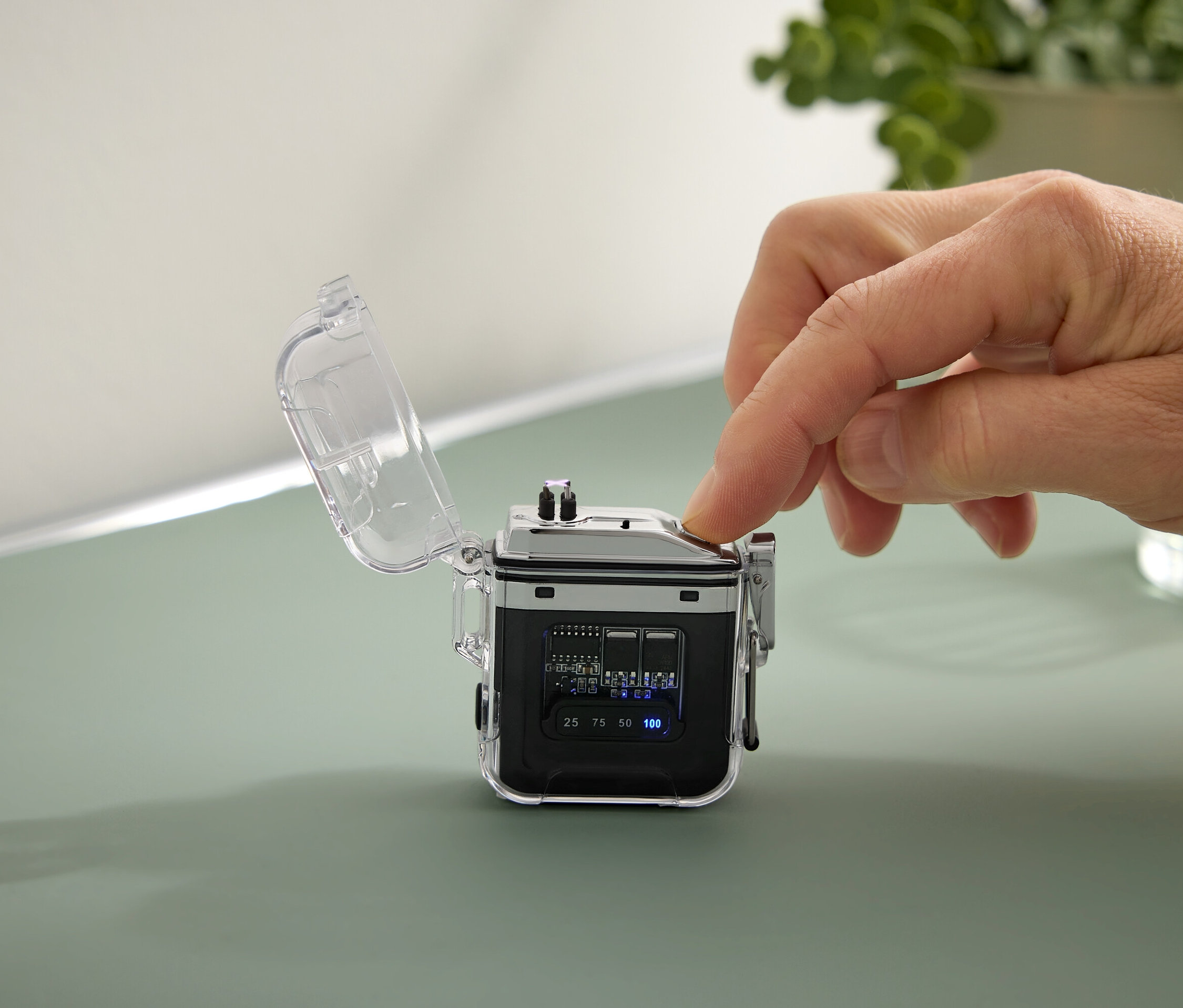 Ruka stiskne tlačítko na malém černém zařízení s průhledným pouzdrem.