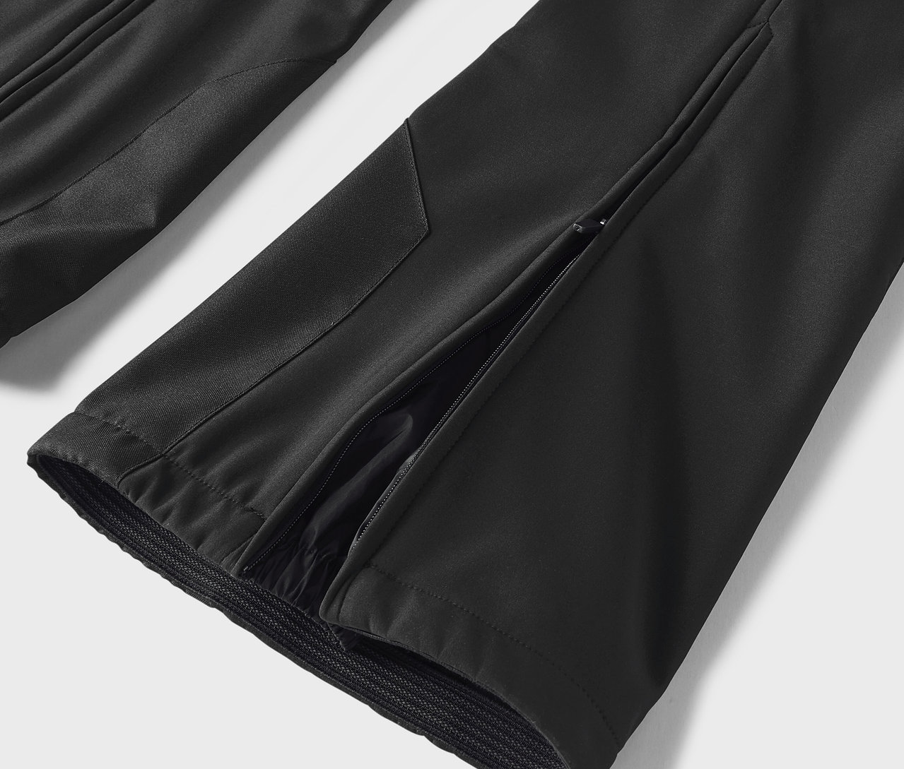 Detail černých kalhot s rozparkem na boku.