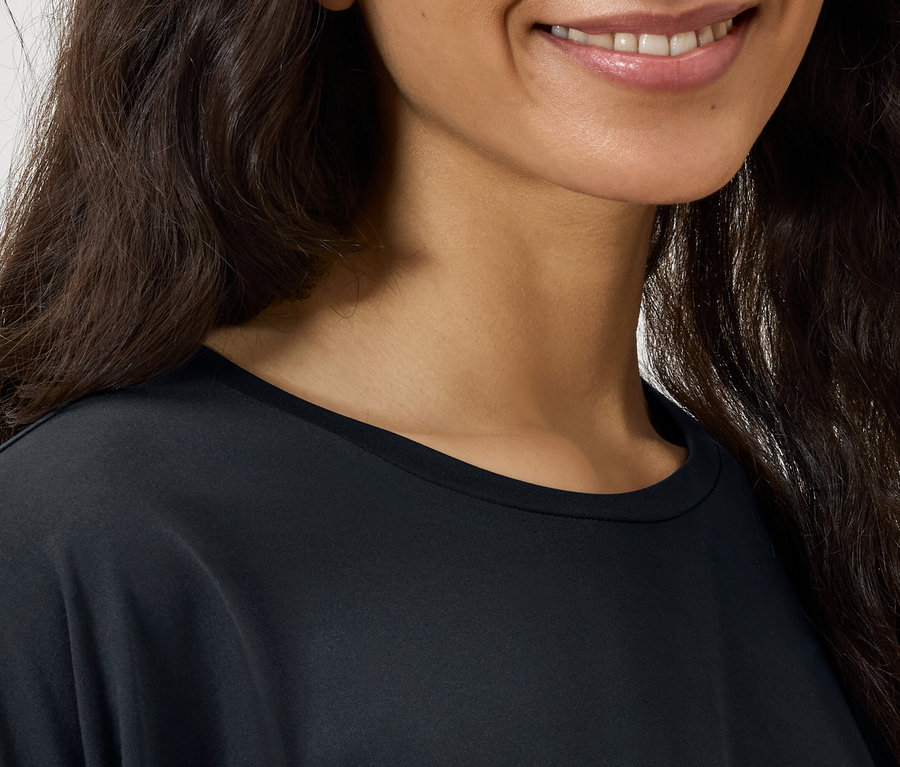 Detail dámské tváře s tmavými vlnitými vlasy a černým tričkem.