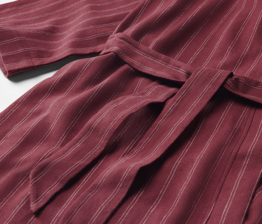 Detail of a maroon striped robe with a tied belt.