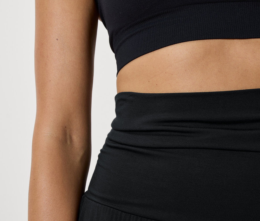 Detail dámského černého sportovního topu a legín.