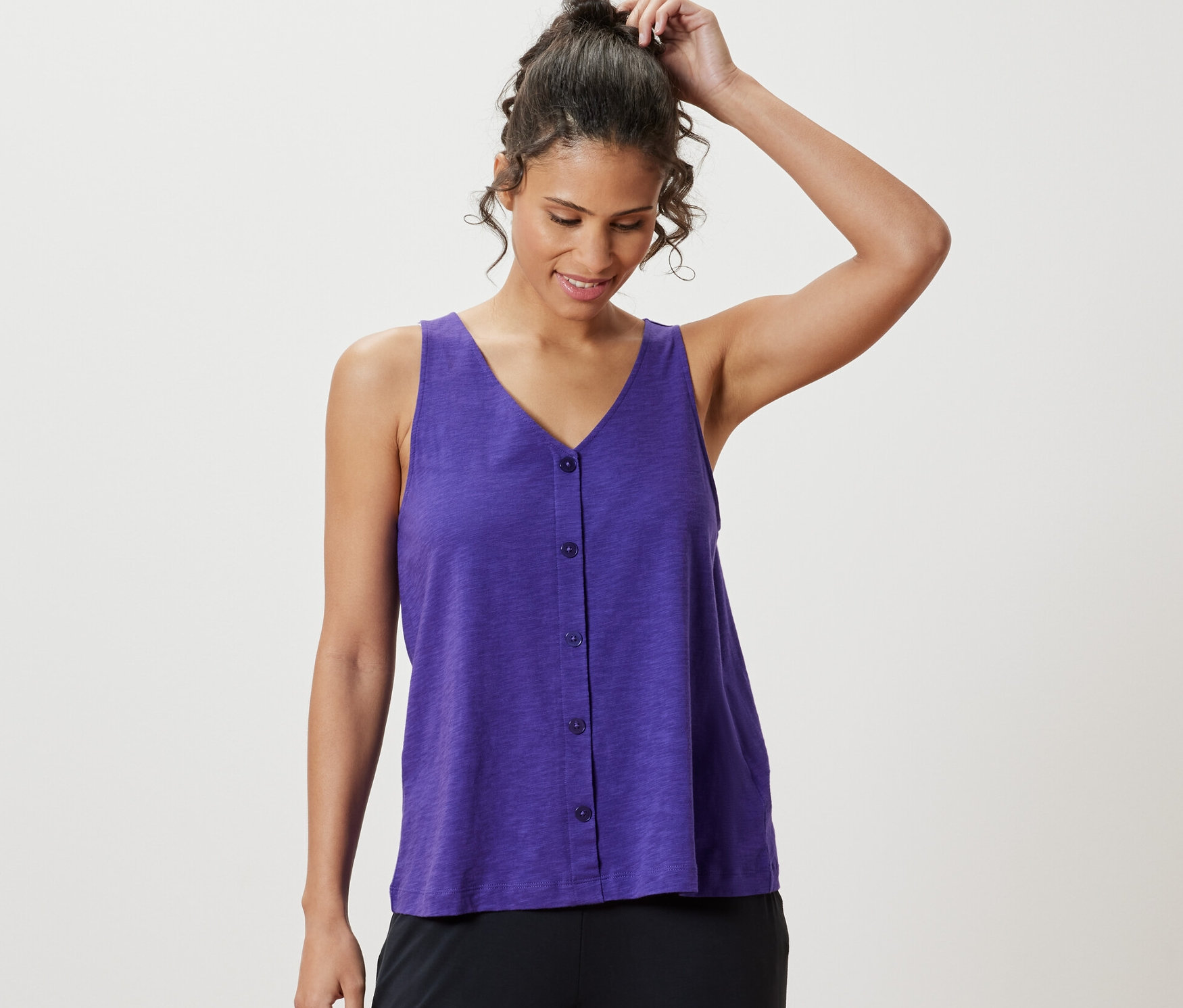 Žena si upravuje vlasy a má na sobě fialový top z modalové směsi.