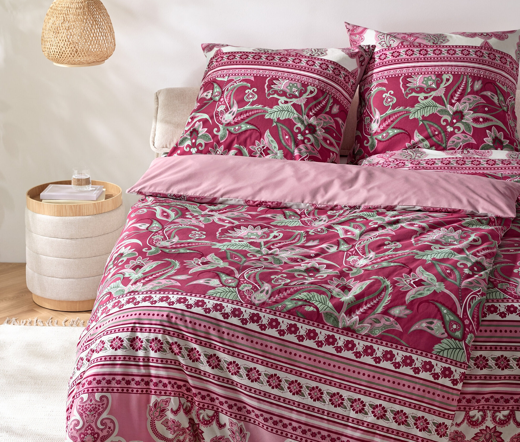 Ložní souprava s kašmírovým vzorem na posteli s nočním stolkem a lampou.