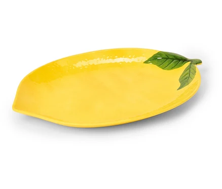 Žlutý, podlouhlý keramický talíř ve tvaru citronu se zelenými listy na jednom konci.