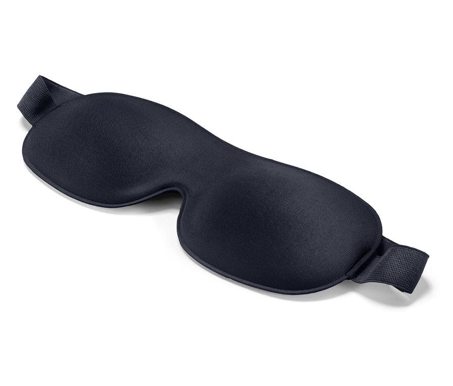 Na bílém pozadí leží tmavě modrá maska na spaní.