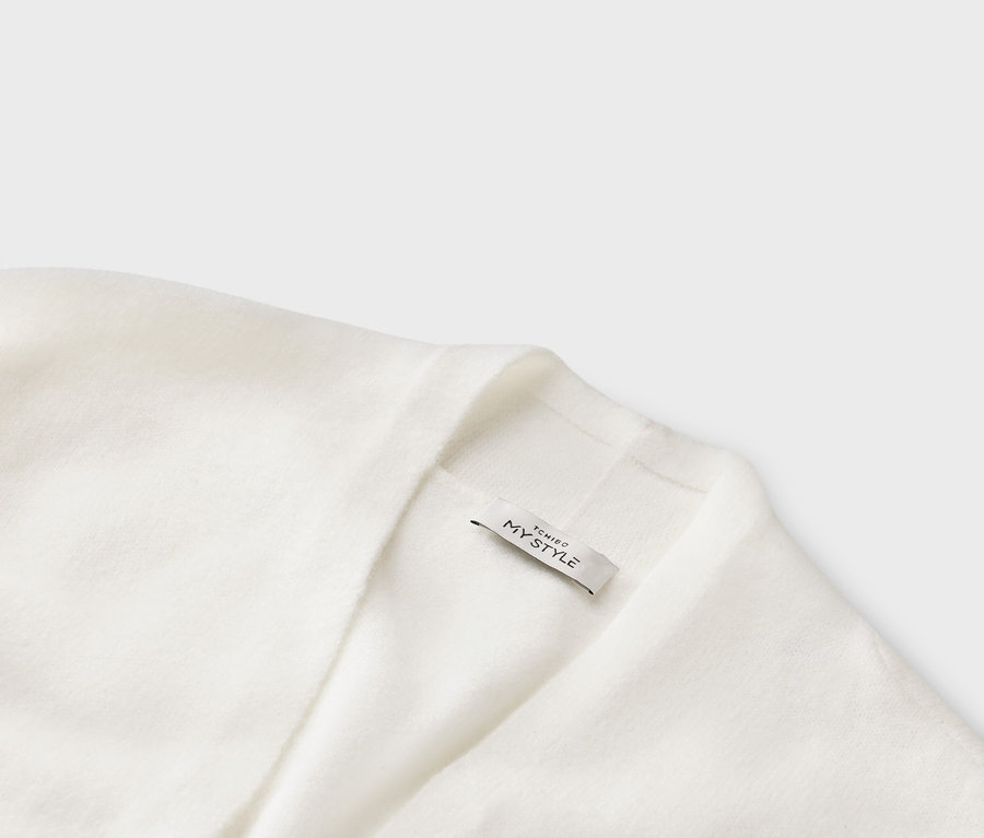 Detailní záběr na bílý pletený kardigan s etiketou s nápisem „TCHIBO MY STYLE“.