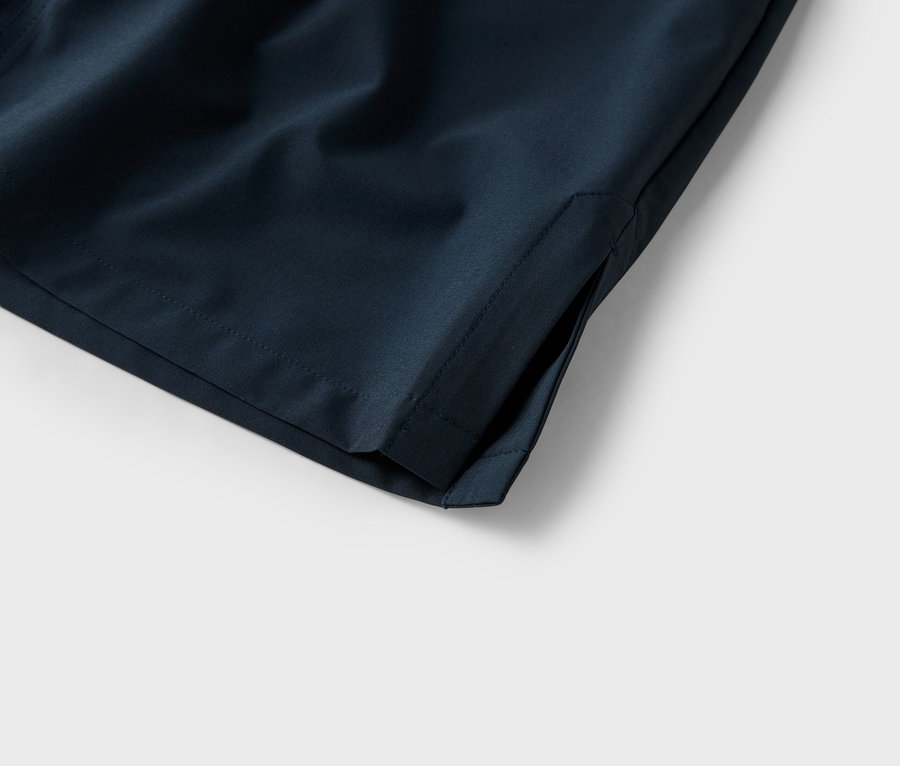 Detail kapsy tmavě modrých šortek na bílém pozadí.