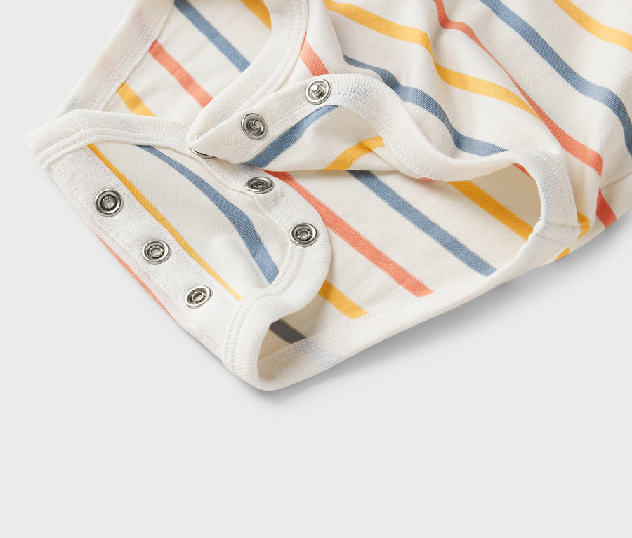 Detailní záběr na bílé dětské body s barevnými pruhy a patentkami.