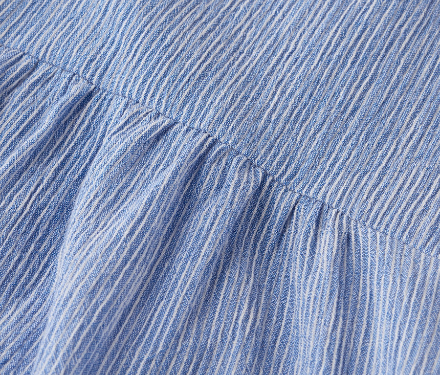 Detailní záběr na modrobílou pruhovanou látku s nařasenými detaily.