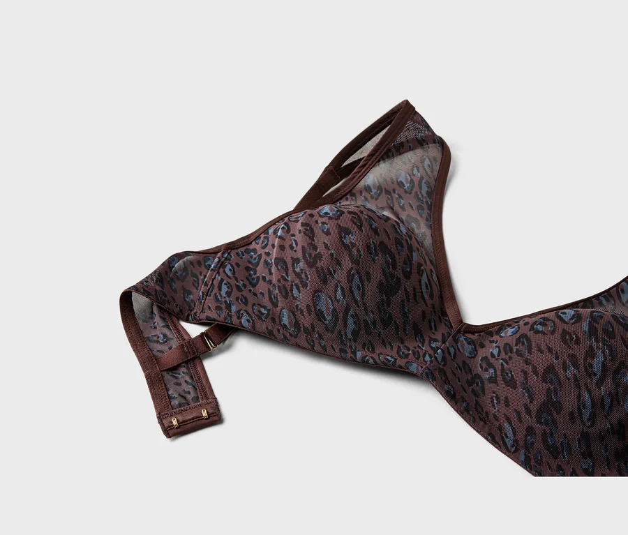 Detail hnědé podprsenky s modro-černým leopardím vzorem, vyrobené z průhledné síťoviny, ukazující jedno ramínko a zadní pás s háčky.