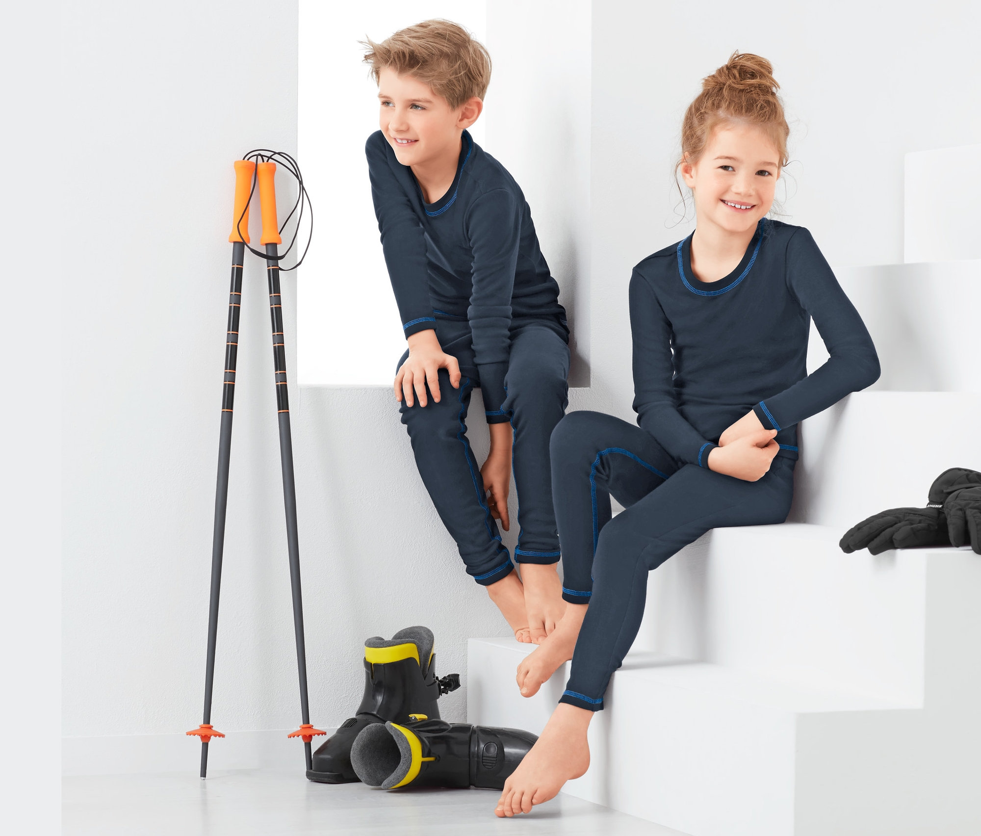 Chlapec a dívka sedí na bílých schodech a mají na sobě funkční spodní prádlo.