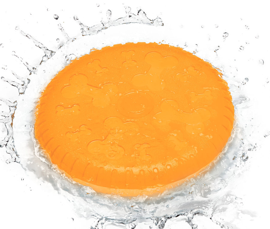 Oranžový létající talíř pro psy ve stříkající vodě.