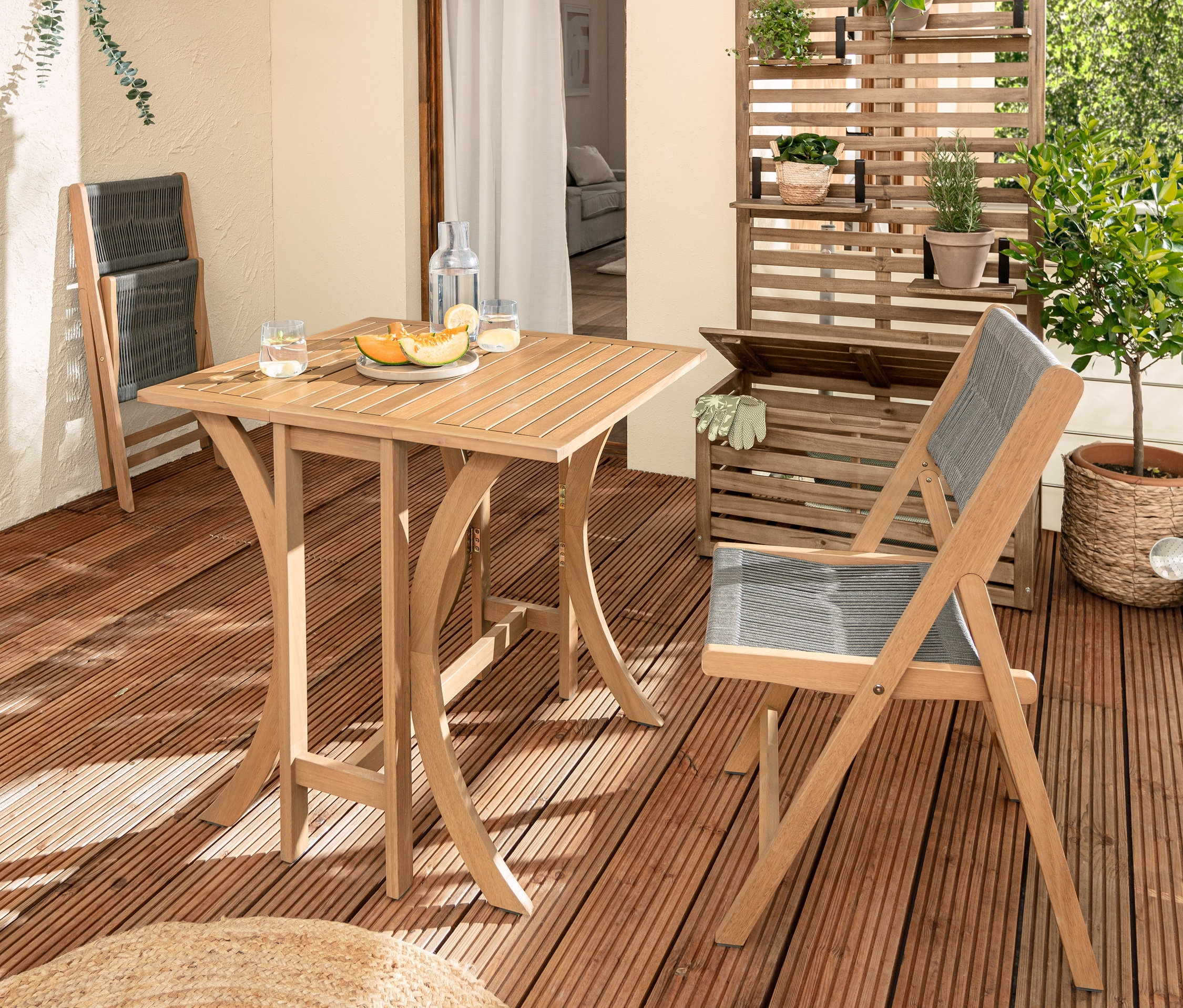 Balkon s dřevěným skládacím setem »Lenja« s textilním výpletem, balkonovou lavicí »Lenja« se zástěnou a úložnou truhlou a balkonovou zástěnou.