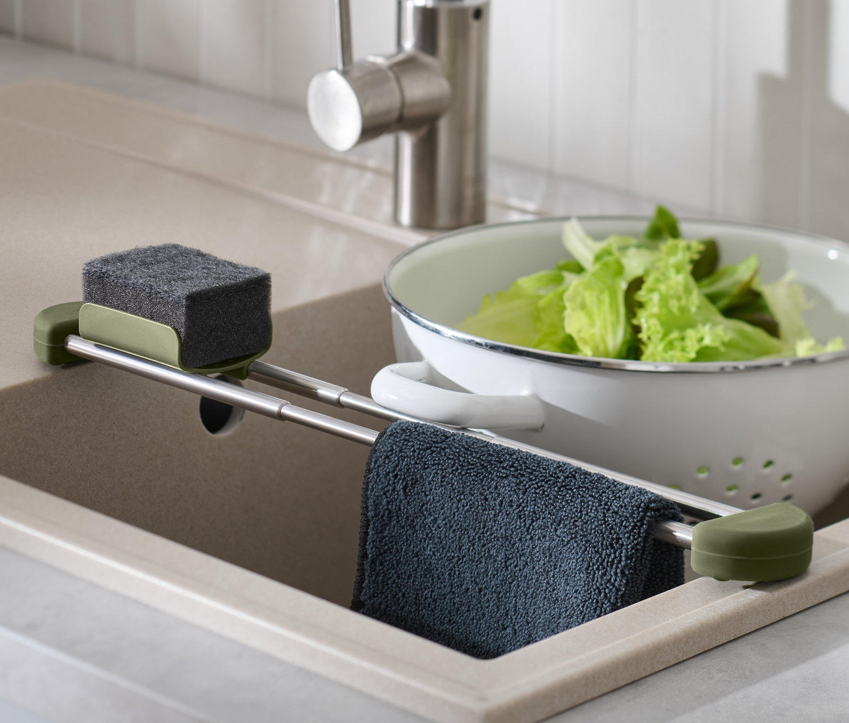 V dřezu je výsuvný organizér na dřez se houbičkou, hadrem a salátem v cedníku.
