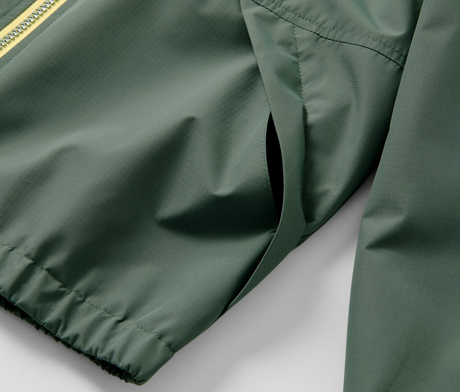 Detail zelené dětské sportovní funkční bundy s žlutým zipem.